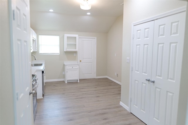interior space featuring vaulted ceiling, a sink, and light wood-type flooring
