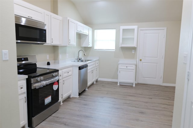 kitchen featuring white cabinets, stainless steel appliances, a sink, and lofted ceiling
