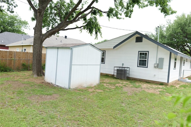 back of house with a lawn, fence, an outbuilding, and a shed
