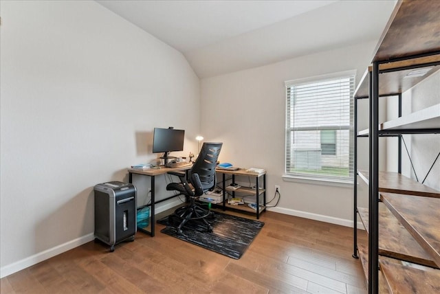 office featuring baseboards, vaulted ceiling, a wealth of natural light, and wood finished floors