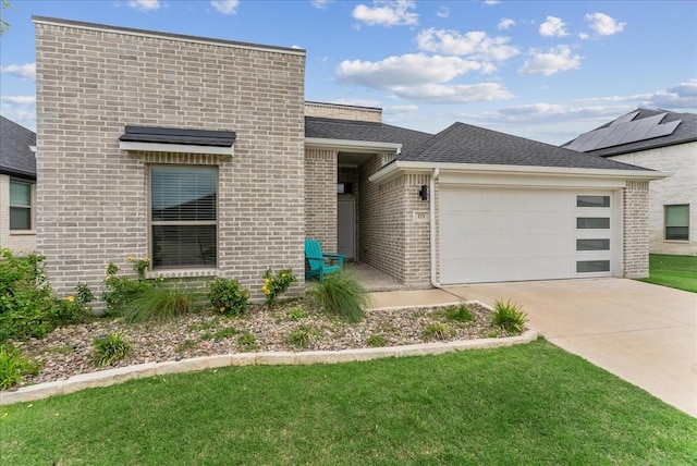 view of front of home featuring a front yard, roof with shingles, brick siding, an attached garage, and driveway