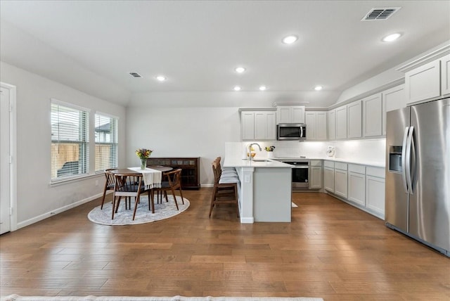 kitchen with a kitchen breakfast bar, appliances with stainless steel finishes, a sink, and visible vents