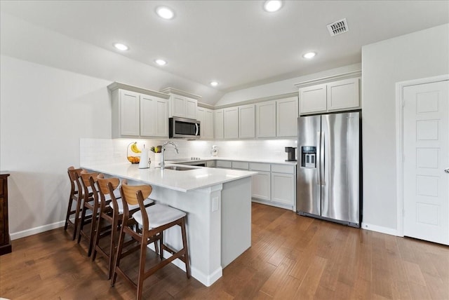 kitchen featuring visible vents, tasteful backsplash, a sink, a peninsula, and stainless steel appliances