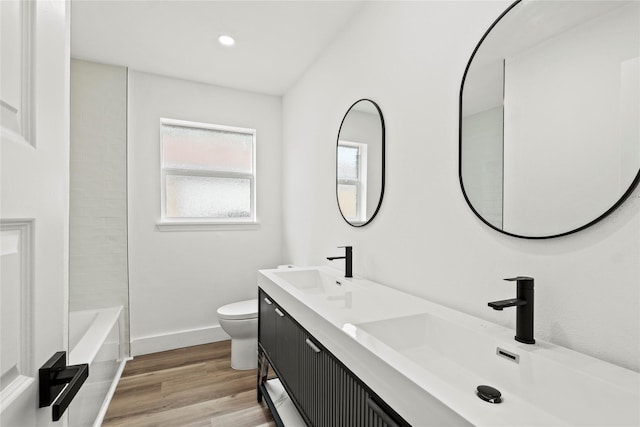 7734 Bruton Rd, Dallas, TX 75217 - bathroom with toilet, baseboards, a sink, and wood finished floors