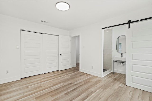 7734 Bruton Rd, Dallas, TX 75217 - unfurnished bedroom featuring visible vents, a barn door, baseboards, a closet, and light wood finished floors