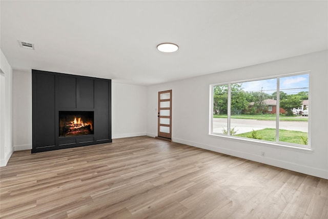7734 Bruton Rd, Dallas, TX 75217 - unfurnished living room with visible vents, light wood-style flooring, baseboards, and a fireplace
