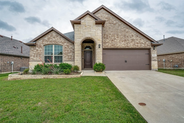 french country home with driveway, a garage, brick siding, a front lawn, and stone siding