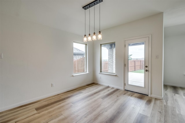 unfurnished dining area with baseboards and light wood finished floors