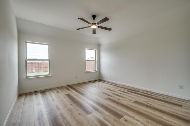 spare room featuring light wood-style floors, baseboards, plenty of natural light, and a ceiling fan
