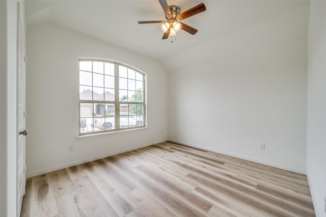 spare room featuring baseboards, ceiling fan, vaulted ceiling, and light wood-style flooring