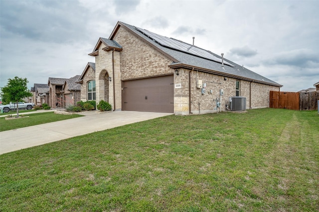 view of property exterior with driveway, a lawn, central air condition unit, roof mounted solar panels, and an attached garage