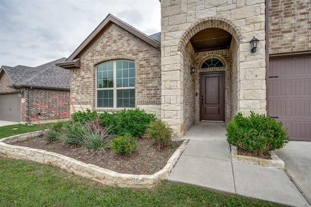 doorway to property featuring brick siding, stone siding, and a garage