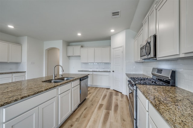 kitchen with visible vents, arched walkways, a sink, backsplash, and stainless steel appliances