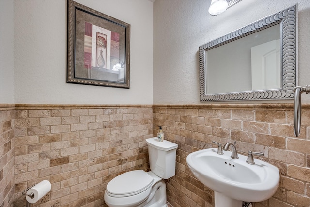 217 Brick Row Dr, Richardson, TX 75081 - bathroom with toilet, tile walls, wainscoting, and a sink