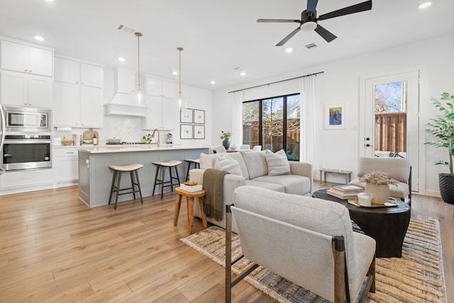 living area with light wood-style floors, a ceiling fan, recessed lighting, and visible vents