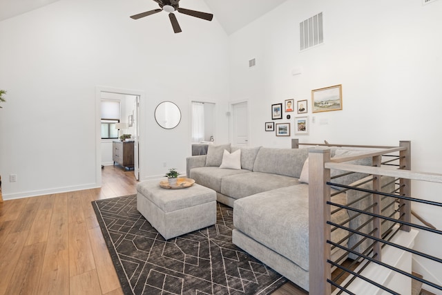 living room featuring ceiling fan, wood-type flooring, high vaulted ceiling, baseboards, and visible vents