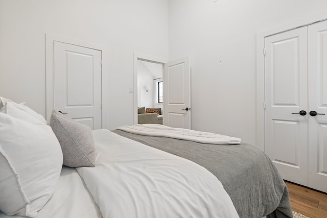 bedroom with a closet, wood finished floors, and a towering ceiling
