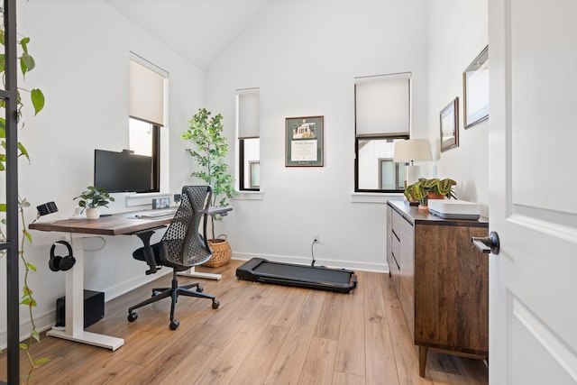 office featuring baseboards, vaulted ceiling, and light wood-type flooring