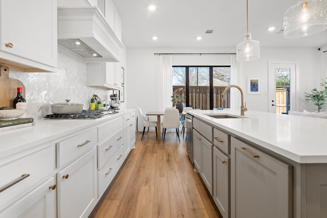 kitchen featuring a sink, light countertops, decorative backsplash, custom range hood, and gray cabinetry