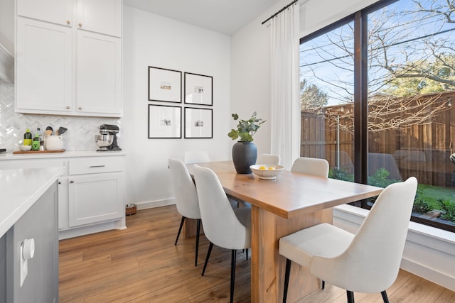 dining area with baseboards and light wood-style flooring