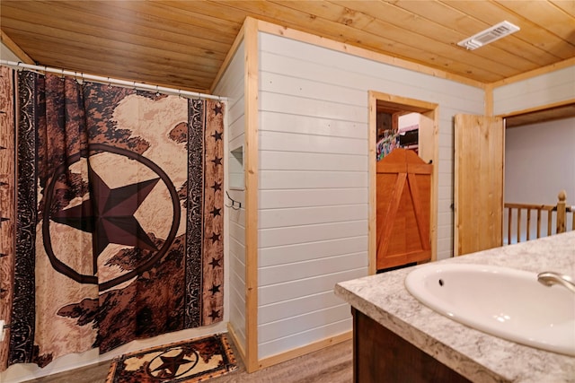 bathroom with wooden walls, vanity, curtained shower, visible vents, and wood ceiling