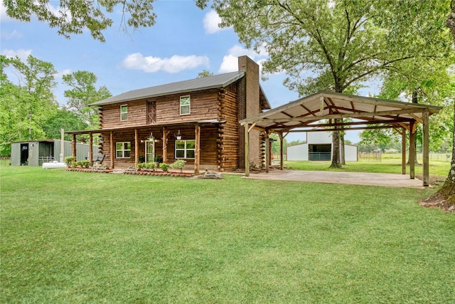 rear view of house featuring an outdoor structure, log exterior, a lawn, and a chimney