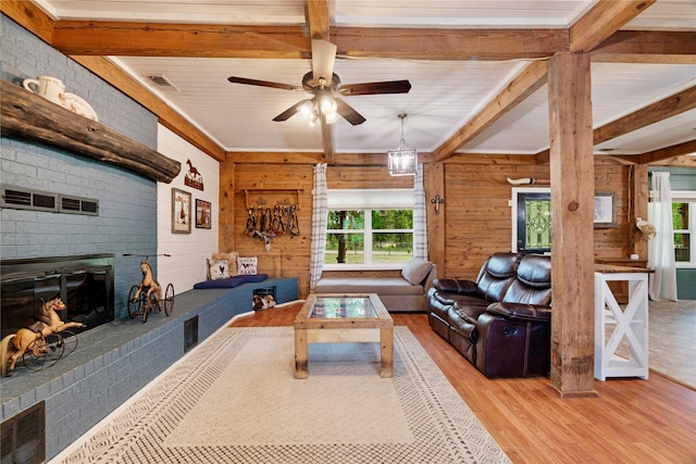 living room featuring wood walls, a brick fireplace, wood finished floors, and a healthy amount of sunlight