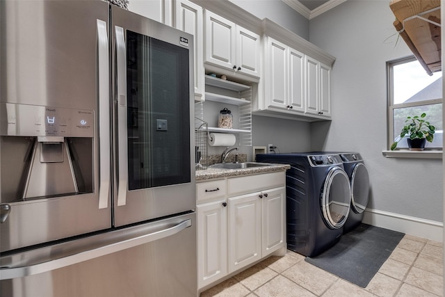 washroom with crown molding, cabinet space, a sink, baseboards, and washer and clothes dryer