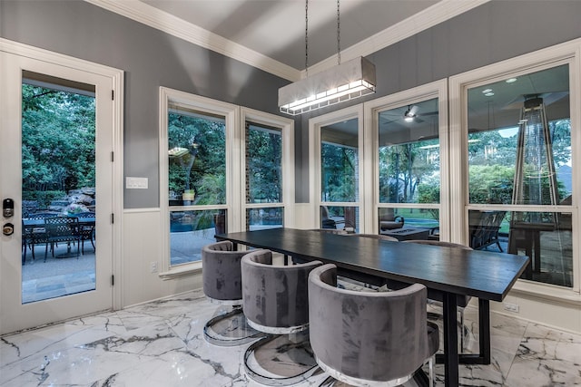 dining area featuring crown molding, wainscoting, marble finish floor, and a decorative wall