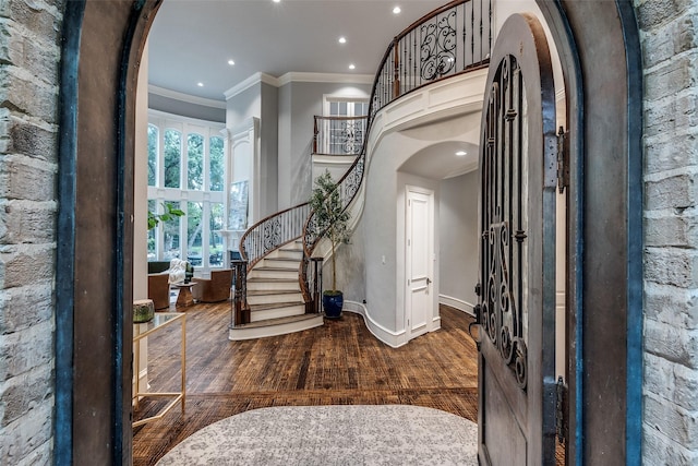 foyer with crown molding, arched walkways, stairs, wood finished floors, and recessed lighting