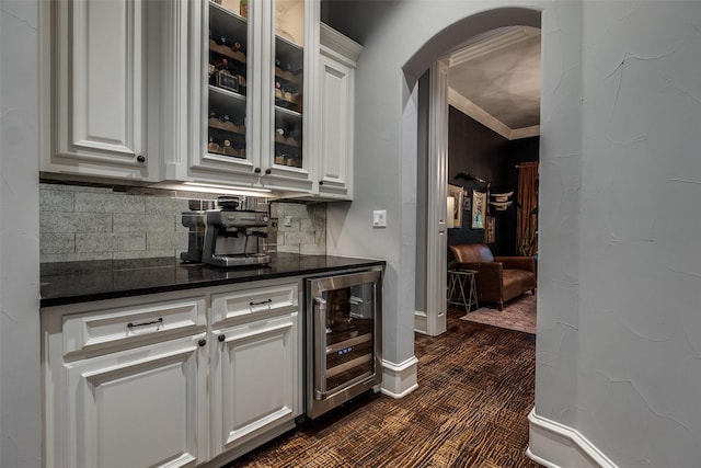 bar featuring wine cooler, arched walkways, tasteful backsplash, and dark colored carpet