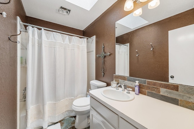 full bathroom featuring toilet, a skylight, a textured wall, and vanity
