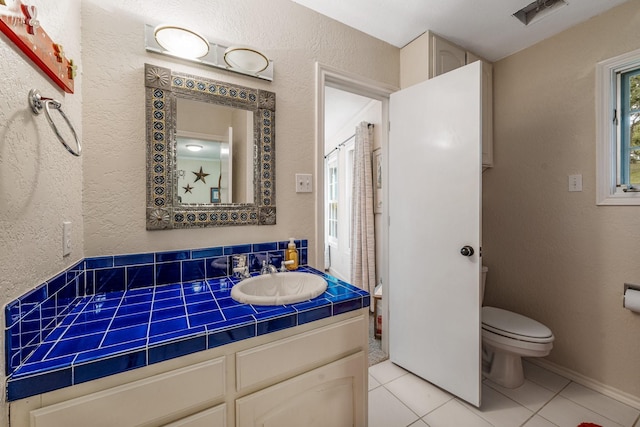 full bathroom with vanity, a textured wall, tile patterned floors, and toilet