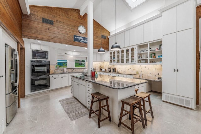 kitchen with a breakfast bar area, tasteful backsplash, high vaulted ceiling, black appliances, and white cabinetry