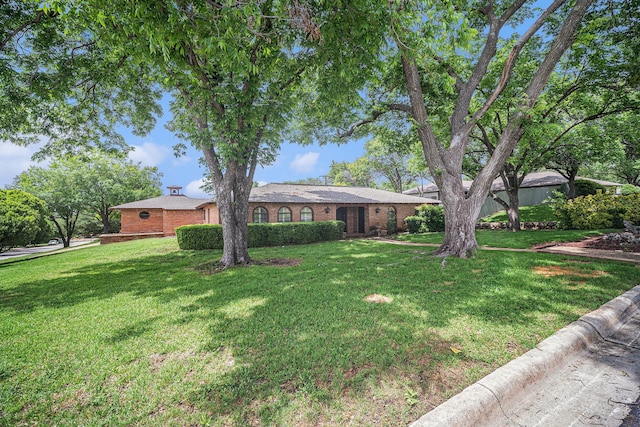single story home with brick siding, a chimney, and a front yard