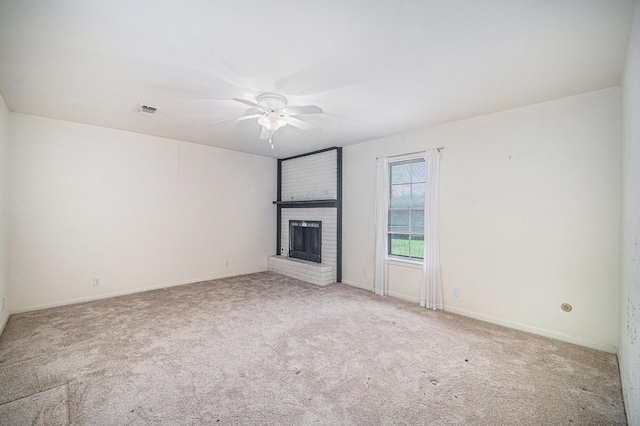 unfurnished living room with a ceiling fan, a brick fireplace, carpet floors, visible vents, and baseboards
