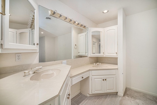 bathroom featuring recessed lighting, double vanity, baseboards, and a sink