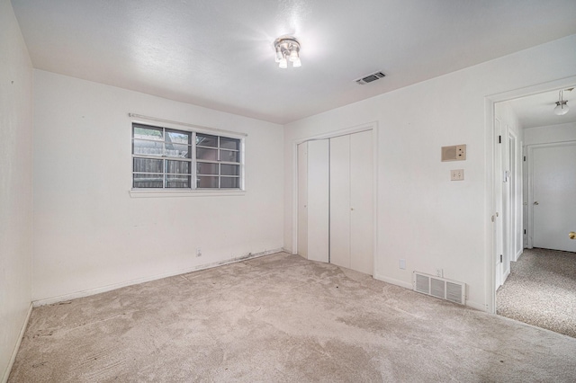 unfurnished bedroom with a closet, visible vents, and carpet