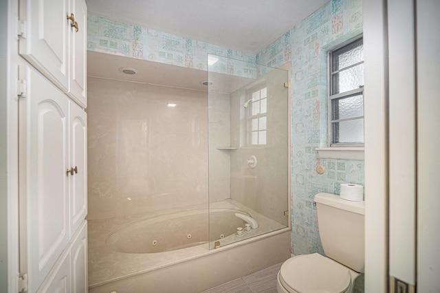 bathroom with a combined bath / shower with jetted tub, wallpapered walls, and toilet