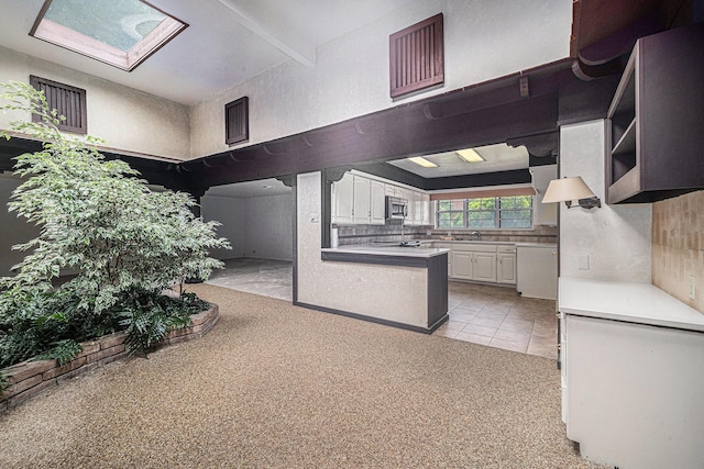 kitchen featuring stainless steel microwave, a peninsula, open shelves, white cabinetry, and light countertops