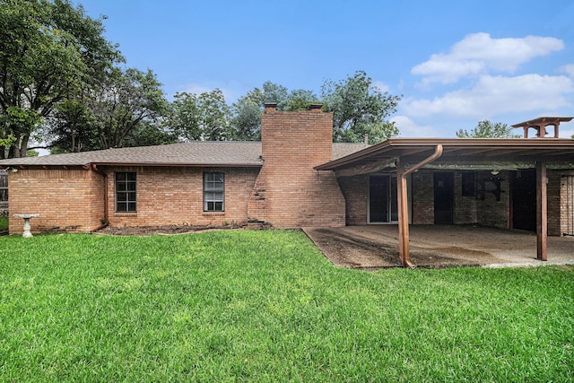 rear view of property featuring brick siding, a patio area, a chimney, and a lawn