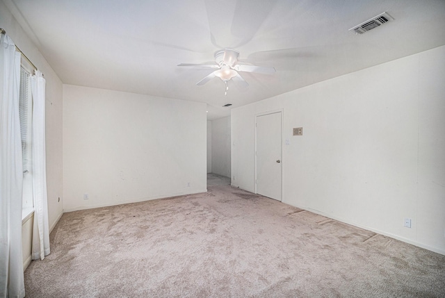 unfurnished room with light colored carpet, a ceiling fan, and visible vents