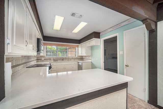kitchen featuring visible vents, a sink, a peninsula, decorative backsplash, and appliances with stainless steel finishes