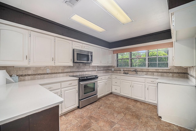 kitchen with a sink, white cabinetry, light countertops, tasteful backsplash, and appliances with stainless steel finishes