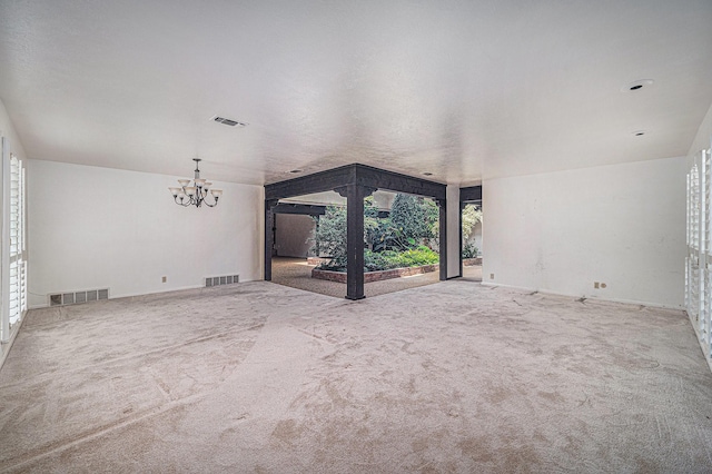 unfurnished living room featuring carpet floors, a notable chandelier, and visible vents
