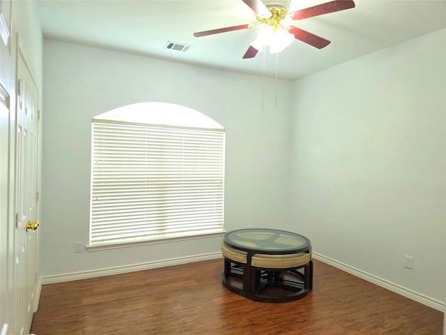 interior space with visible vents, a ceiling fan, baseboards, and wood finished floors