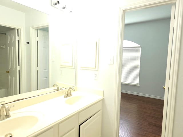bathroom with double vanity, a sink, baseboards, and wood finished floors