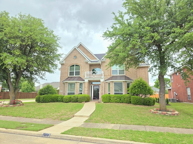 traditional-style house featuring a front lawn, fence, a standing seam roof, brick siding, and central AC unit
