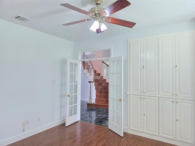 unfurnished bedroom featuring a ceiling fan, french doors, visible vents, wood finished floors, and baseboards