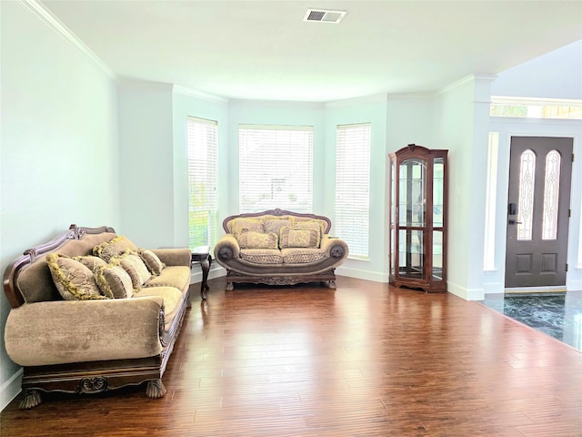 living area with baseboards, visible vents, dark wood-style floors, and ornamental molding